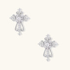 White gold-plated baroque cross studs with zirconia stones and ornate scrollwork on cream background.