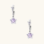 White gold plated huggie earrings with clear CZ accents and dangling lavender star-shaped crystals on cream background