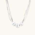Sterling silver multi-strand necklace with three brushed round beads on cream background