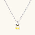 Chrome egg-shaped pendant with kawaii face, yellow bow, and pearl detail on silver chain against white background