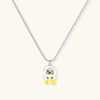 Chrome egg-shaped pendant with kawaii face, yellow bow, and pearl detail on silver chain against white background