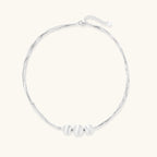 Sterling silver multi-strand necklace with three brushed round beads on cream background