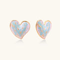 Heart-shaped stud earrings with swirled turquoise and pink enamel in gold-plated frames on cream background