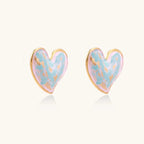 Heart-shaped stud earrings with swirled turquoise and pink enamel in gold-plated frames on cream background