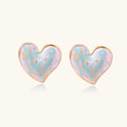 Heart-shaped stud earrings with swirled turquoise and pink enamel in gold-plated frames on cream background