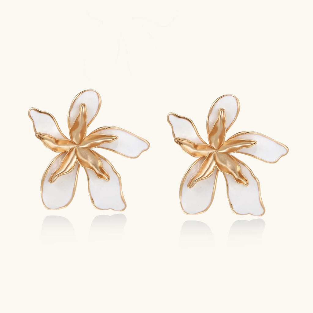 White enamel tropical flower earrings with sculptural gold-plated center and organic petal design on cream background