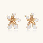 White enamel tropical flower earrings with sculptural gold-plated center and organic petal design on cream background