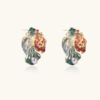 Artistic monstera-shaped earrings with teal, coral, and cream enamel brushstrokes, gold trim, and white pearl accent