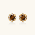 Gold-plated stud earrings with ornate floral frames surrounding cabochon tiger's eye stones and zirconia accents