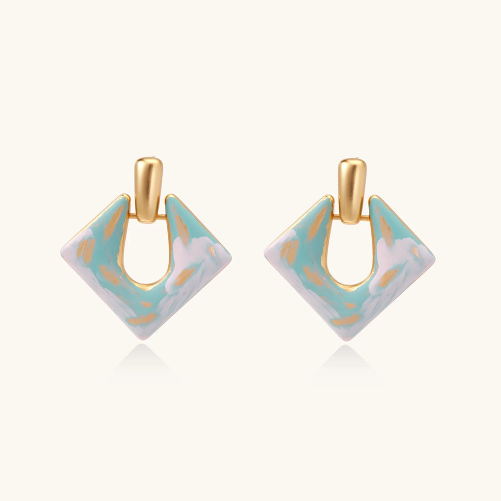 Geometric square enamel earrings with marbled turquoise and lavender pattern, gold U-shaped connector on cream background.