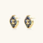 Gold quatrefoil stud earrings with iridescent abalone shell inlay and fleur-de-lis center, accented by four crystals