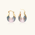 Gold hoop earrings with gradient blue-to-pink enamel in ribbed fan design on beige background