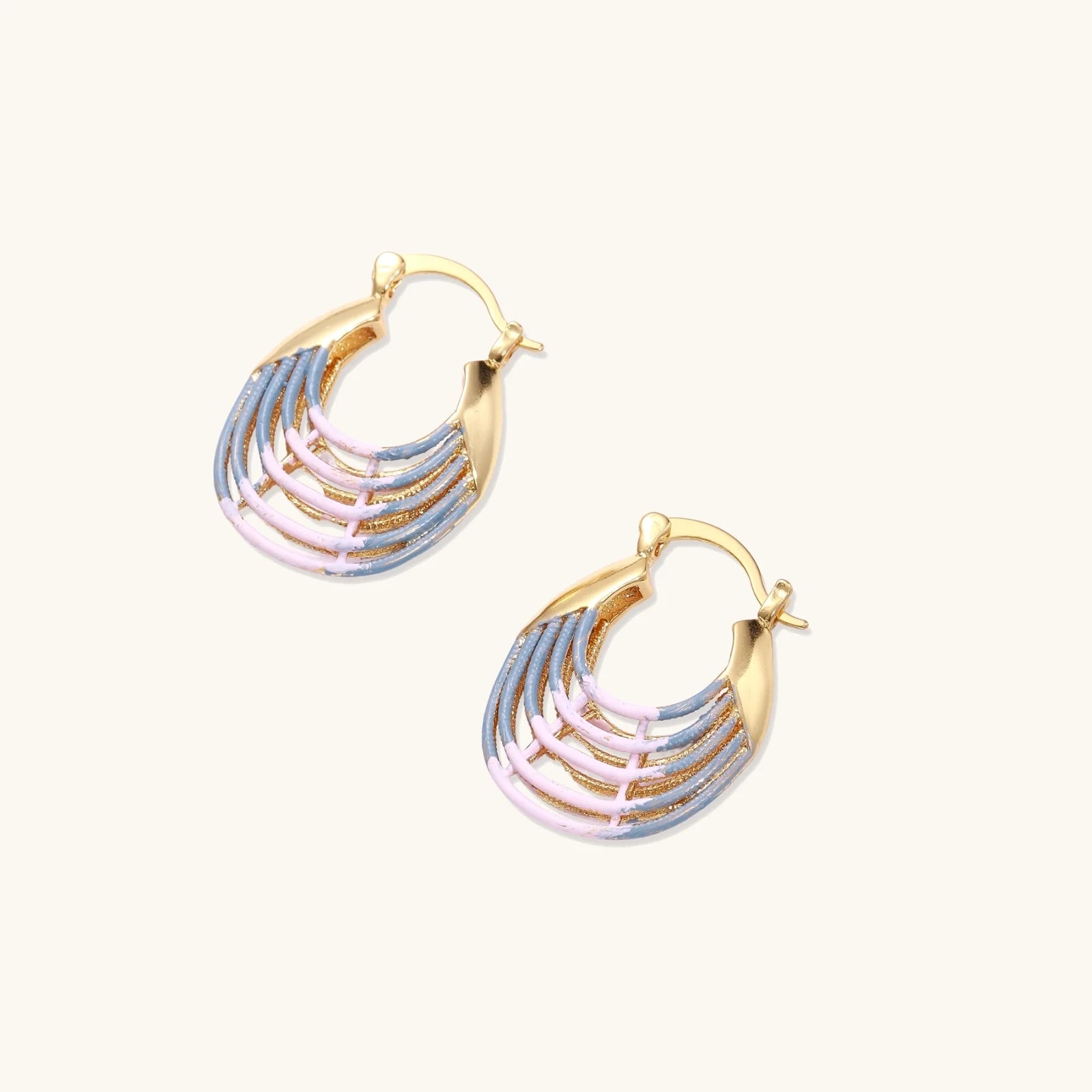 Gold hoop earrings with gradient blue-to-pink enamel in ribbed fan design on beige background