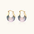 Gold hoop earrings with gradient blue-to-pink enamel in ribbed fan design on beige background