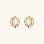 Circular gold stud earrings with iridescent mother-of-pearl center and green zirconia accents on cream background.