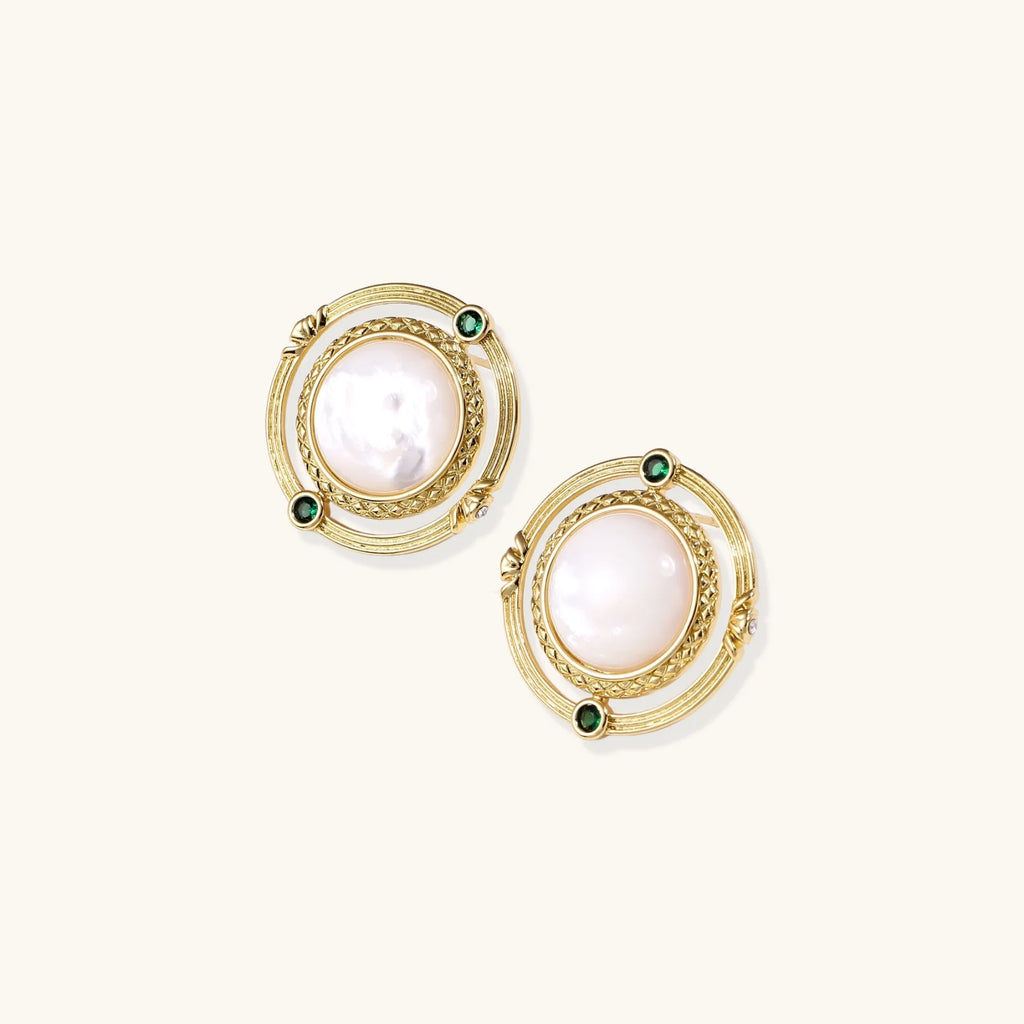 Circular gold stud earrings with iridescent mother-of-pearl center and green zirconia accents on cream background.