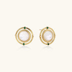 Circular gold stud earrings with iridescent mother-of-pearl center and green zirconia accents on cream background.