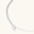 Long sterling silver beaded necklace with graduated sphere design, toggle clasp, and delicate chain extension on white background