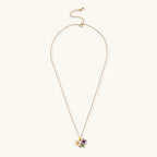 Gold-plated necklace with pink and purple enamel flower pendant featuring crystal accents on cream background