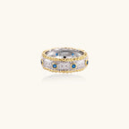 Two-tone ring with brushed silver center, gold beaded edges, and blue zirconia stones on white background.