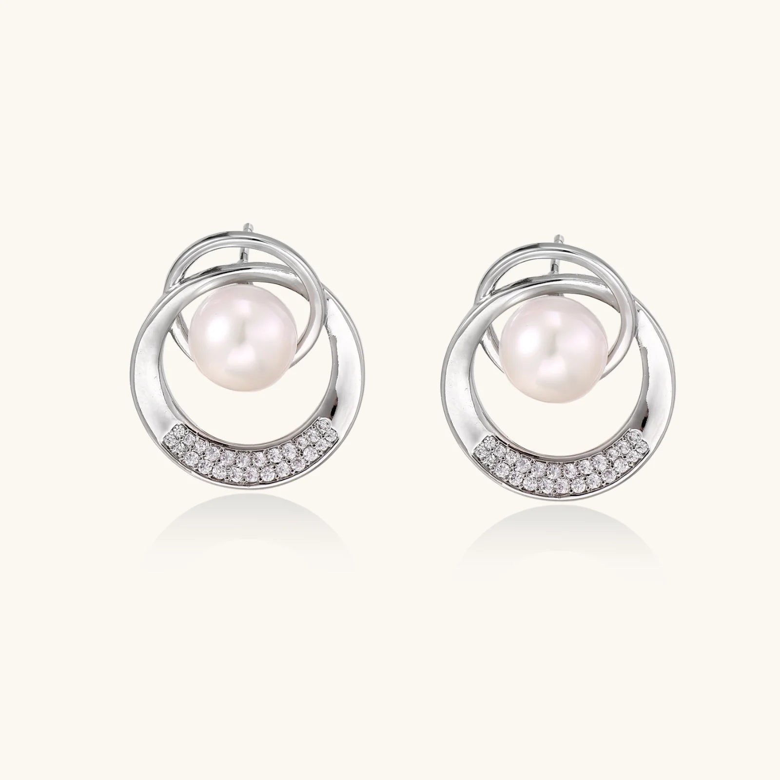 White gold-plated brass earrings with circular design, freshwater pearl center, and diamond accents