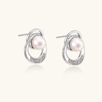White gold-plated brass earrings with circular design, freshwater pearl center, and diamond accents