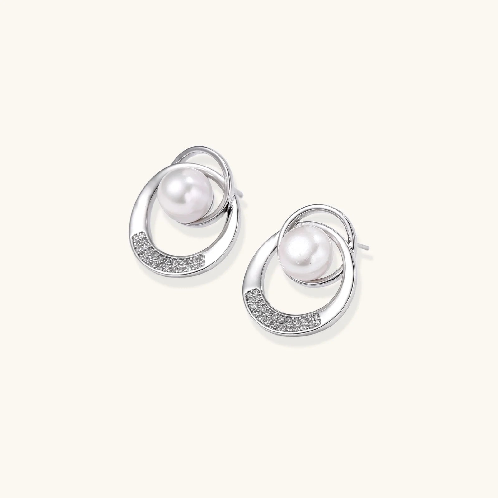 White gold-plated brass earrings with circular design, freshwater pearl center, and diamond accents