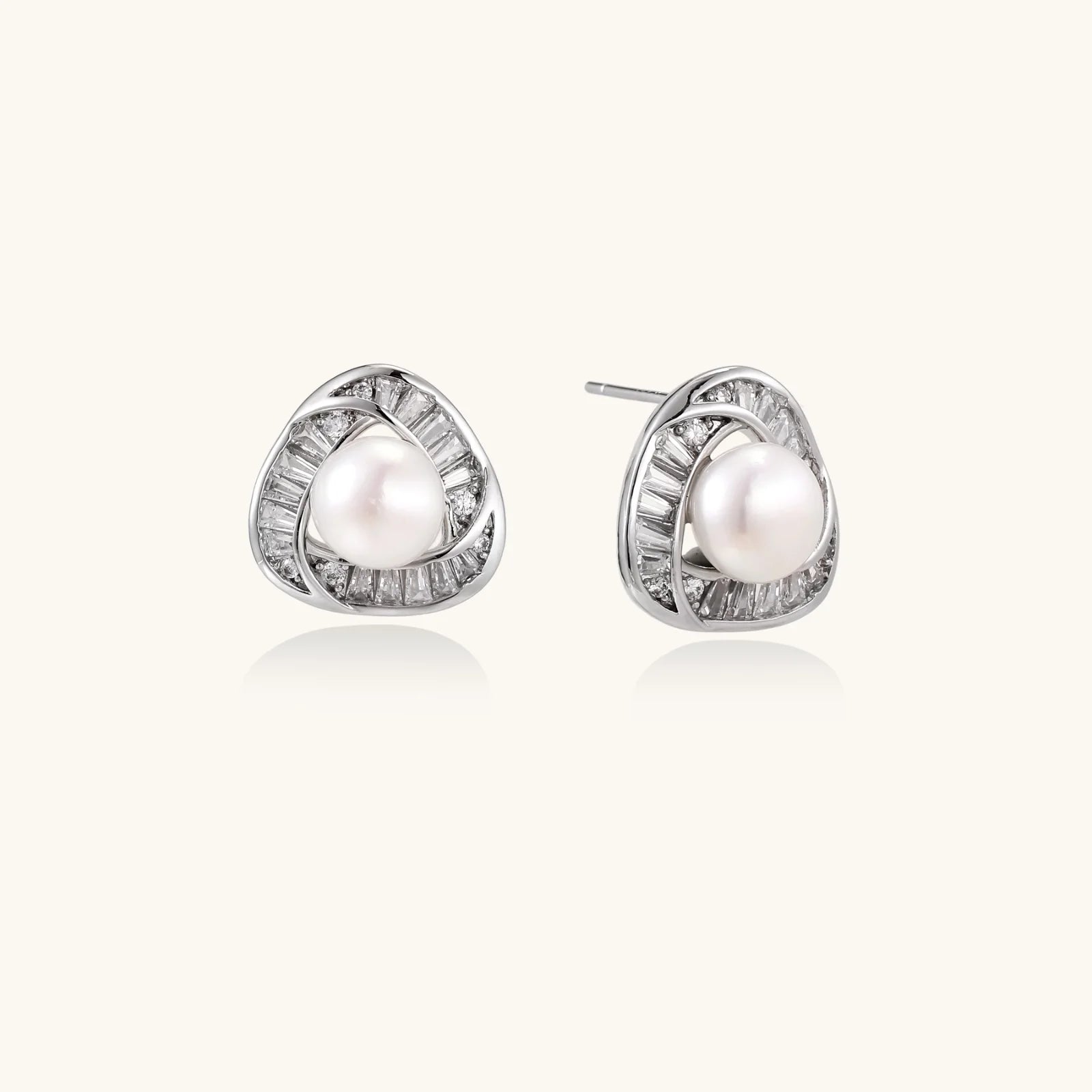 Triangular white gold plated stud earrings with central freshwater pearl and baguette-cut stones on white background
