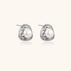 Triangular white gold plated stud earrings with central freshwater pearl and baguette-cut stones on white background