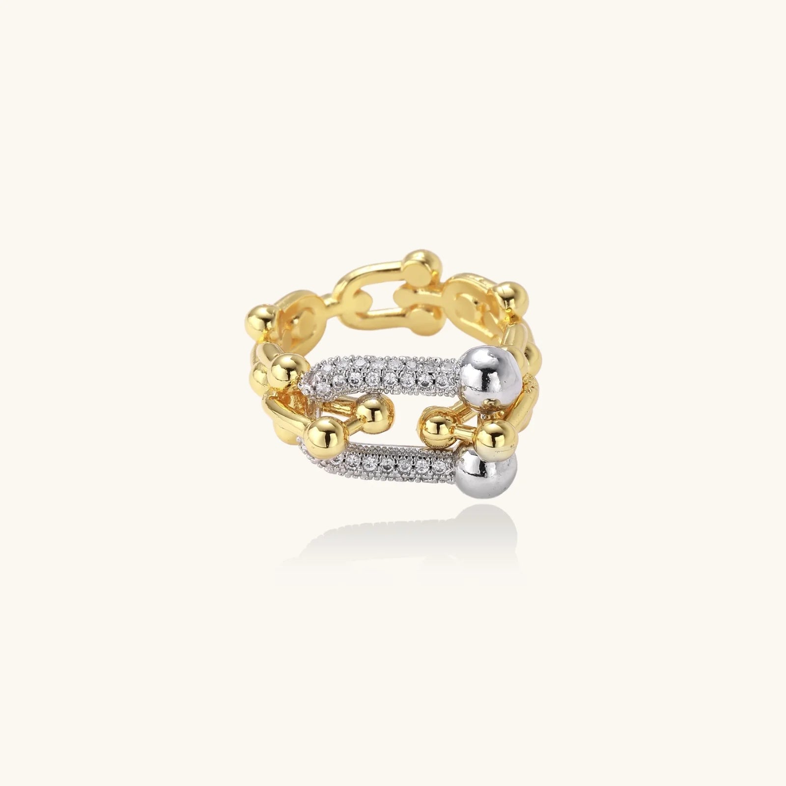 Triple-band gold ring with spherical bead chains and two crystal-pavé bars on cream background