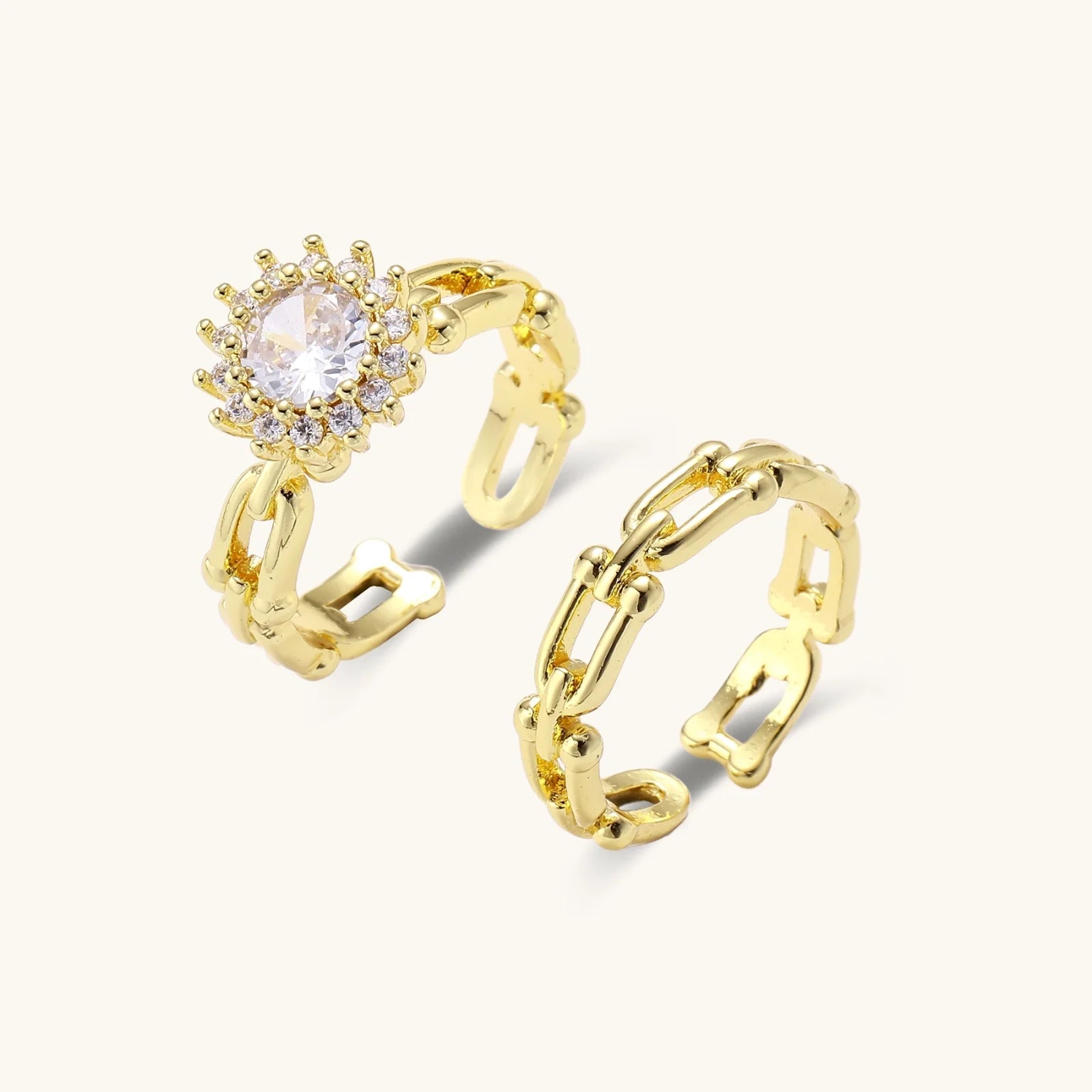 Two adjustable gold rings: chain-link band and halo-style ring with cubic zirconia stones on cream background