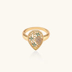 Teardrop-shaped gold-plated ring with turquoise enamel flowers and crystal pavé detail on cream background