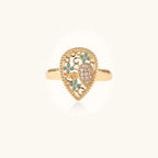 Teardrop-shaped gold-plated ring with turquoise enamel flowers and crystal pavé detail on cream background