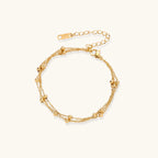 Three-strand gold-plated bracelet with clustered ball beads and adjustable clasp on cream background