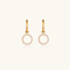 Gold-plated huggie hoop earrings with CZ-studded open circle charms on beige background