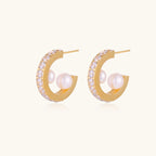 Gold pavé hoop earrings with two freshwater pearls nestled inside the curved design, featuring crystal-studded outer edge.