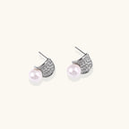 Curved pavé diamond studs in white gold-plated brass cradle lustrous freshwater pearls against cream background