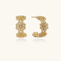 Gold hoop earrings with intricate three-dimensional floral filigree pattern in 14K gold plated brass on cream background
