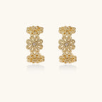 Gold hoop earrings with intricate three-dimensional floral filigree pattern in 14K gold plated brass on cream background
