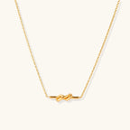 Dainty 18K gold plated necklace with infinity knot pendant on delicate chain against white background