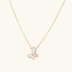 Gold-plated butterfly pendant with iridescent mother of pearl inlay on delicate chain against cream background.