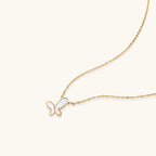 Gold-plated butterfly pendant with iridescent mother of pearl inlay on delicate chain against cream background.