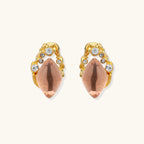 Gold-plated baroque stud earrings with coral-pink liuli stones and cubic zirconia crystals on white background.