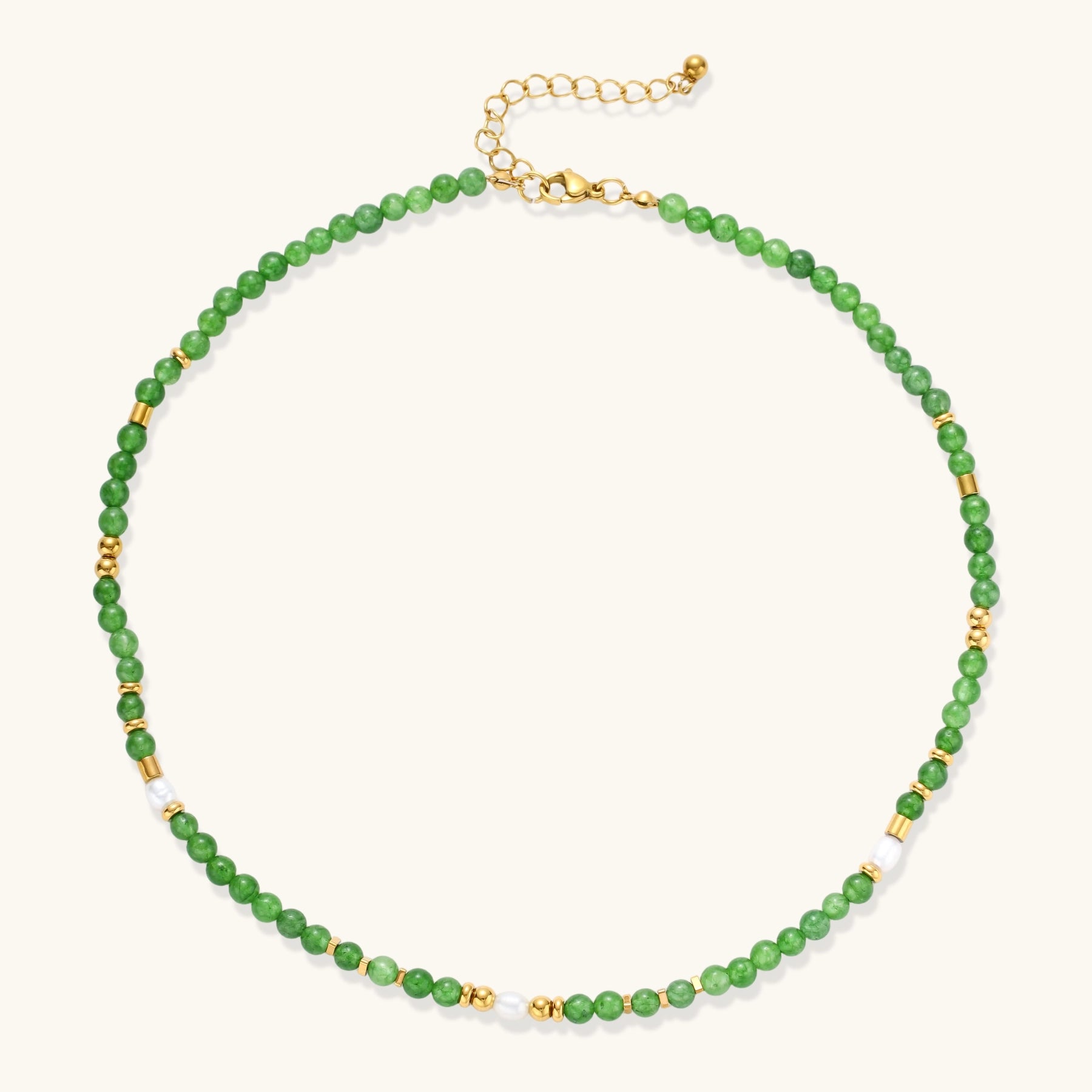 Layered necklace with green stone beads, gold spacers, white accents, and protective eye pendant on cream background.