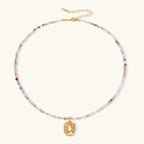Delicate gold-plated necklace with mixed gemstone beads and ornate oval pendant on white background