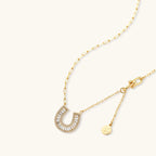 Sparkling horseshoe-shaped jewelry set with AAA cubic zirconia in gold-plated and white gold finishes on cream background.