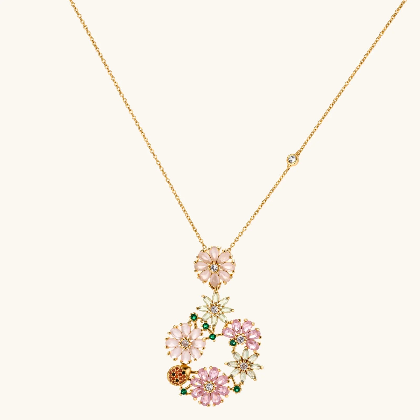 14K gold plated jewelry set with pink and green cubic zirconia flowers arranged in wreath design on cream background