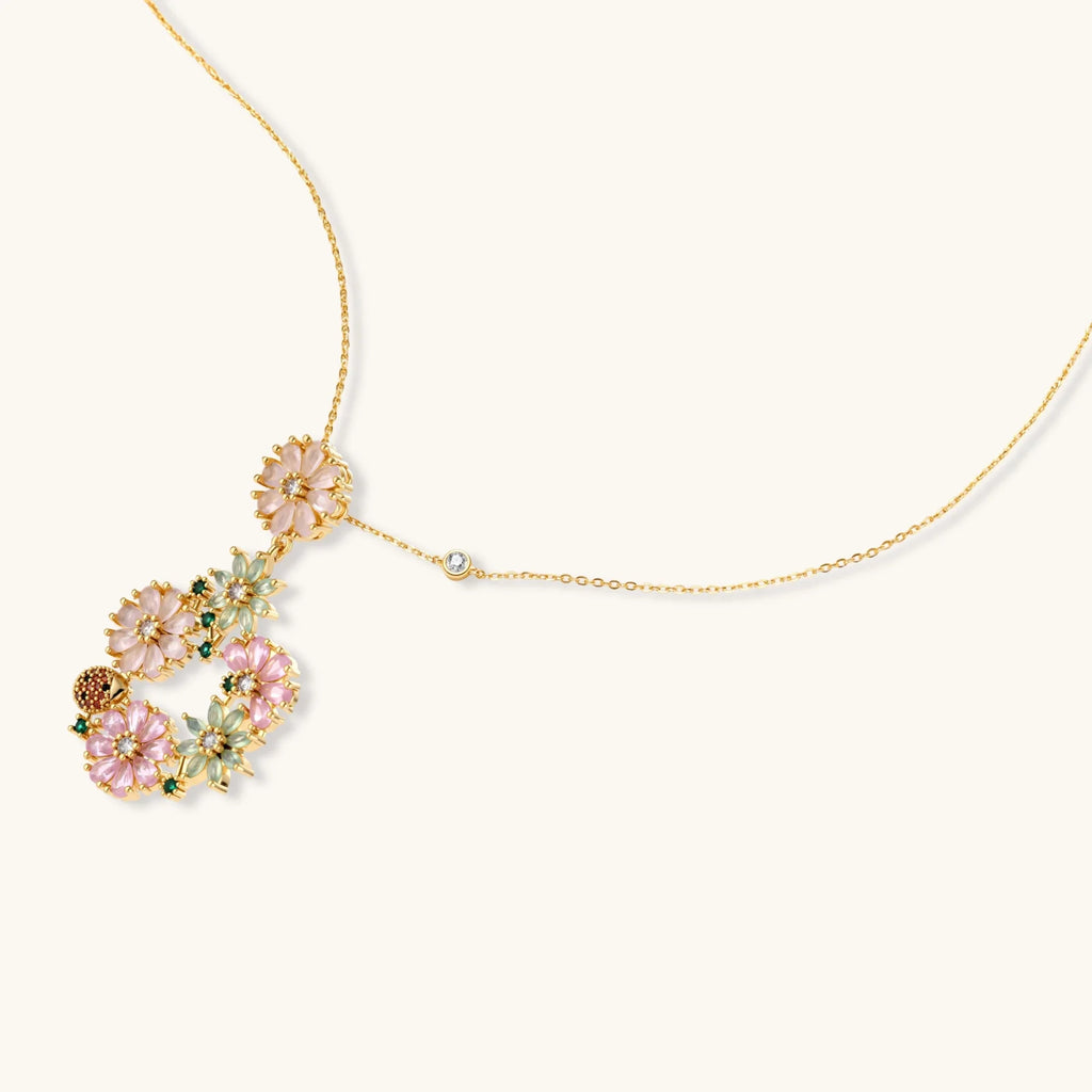 14K gold plated jewelry set with pink and green cubic zirconia flowers arranged in wreath design on cream background
