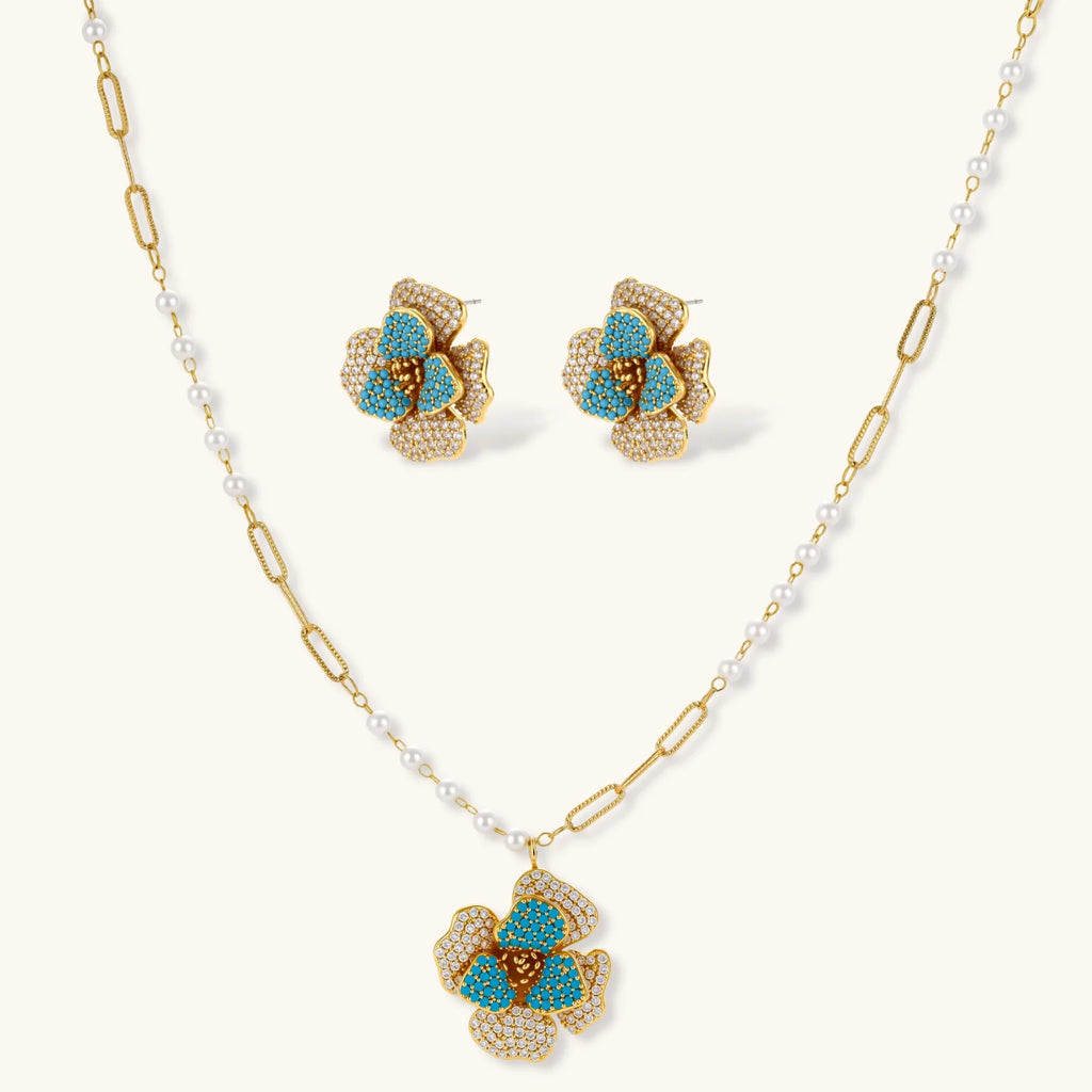 14K gold-plated floral jewelry set with blue cubic zirconia centers and pearl chain details on white background.