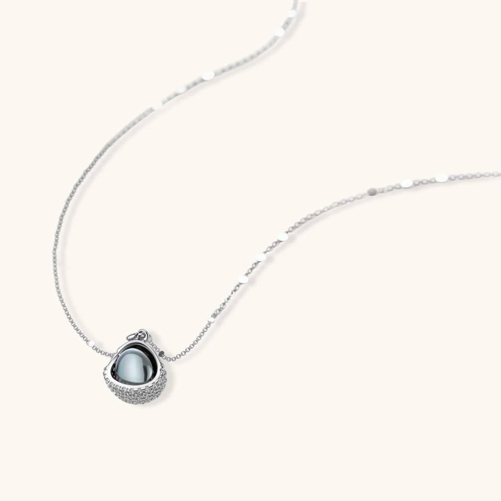 Elegant spherical pendant necklace and earrings set featuring crystal-pavé bottom half in gold or silver finish on white background.